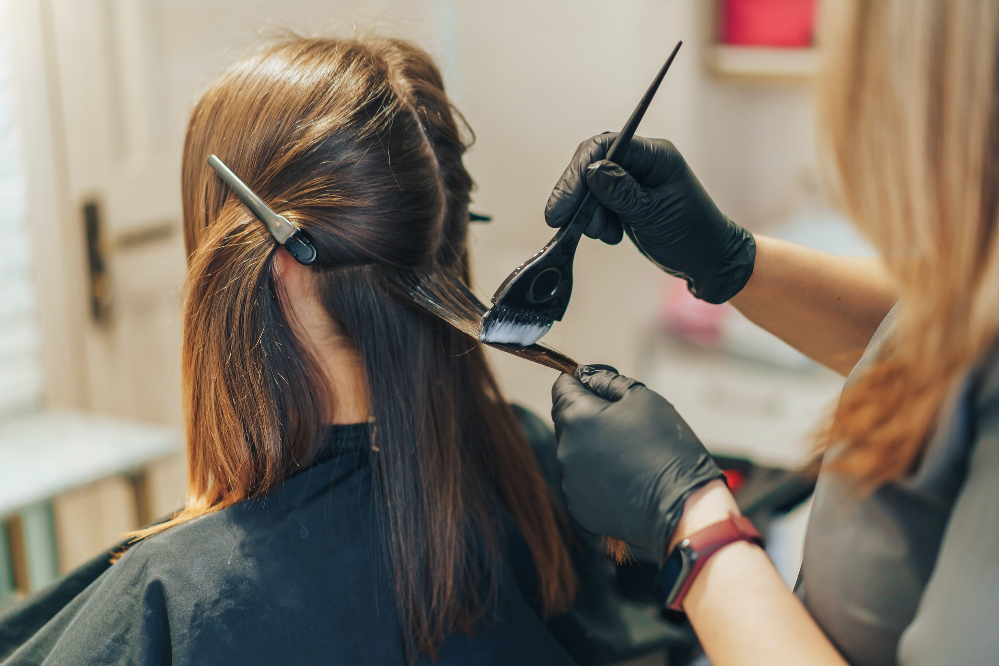 hair stylist dyes hair with a brush with foil